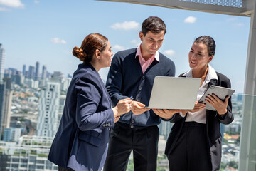 Business team working together on a laptop at outdoor or rooftop office with city background 