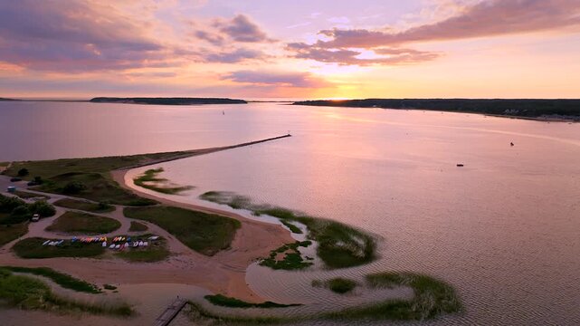 Aerial view of Wellfleet Harbor and Cape Cod Bay at sunset, with tranquil waters reflecting the pastel sky, serene beaches, and distant islands. Wellfleet, Cape Cod, USA.
