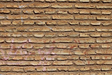 Rustic brick wall with blue paint marks. Urban architectural background, detailed pattern of traditional clay bricks, close-up texture for design, construction and restoration themes