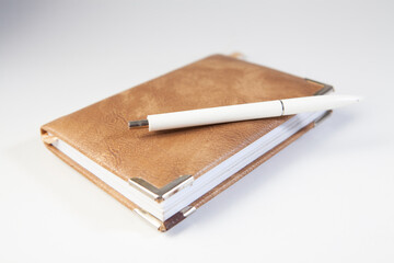 Notebook and pen isolated on white background, close-up.
