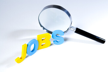 The word job and magnifying glass on white background. Job search concept.