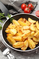 Tasty baked potatoes in frying pan on grey textured table, closeup