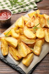 Tasty baked potatoes with rosemary on wooden table, closeup