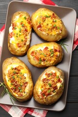 Tasty stuffed baked potatoes on black wooden table, top view