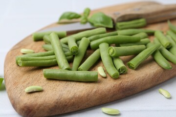 Cut green bean pods and knife on white table, closeup
