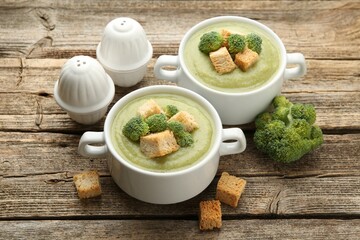 Tasty broccoli cream soup with croutons served on wooden table, closeup