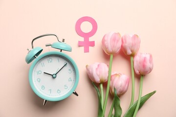 Menopause. Female gender symbol, alarm clock and tulips on beige background, flat lay