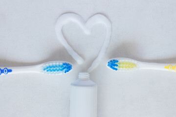 Flat lay composition with heart shape made of toothpaste and  toothbrush  on white background. The concept is dental and oral care products.