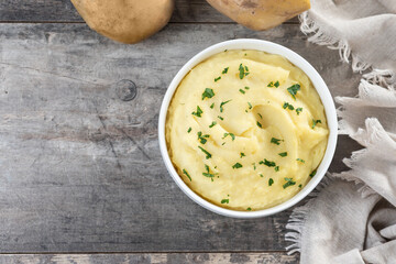 Mashed potatoes in white bowl on wooden table. Top vioew. Copy space
