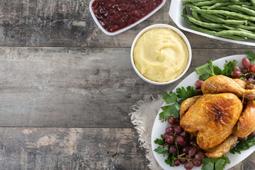 Thanksgiving roasted turkey with mashed potatoes, cranberry sauce and green beans on rustic wooden table. Top view. Copy space