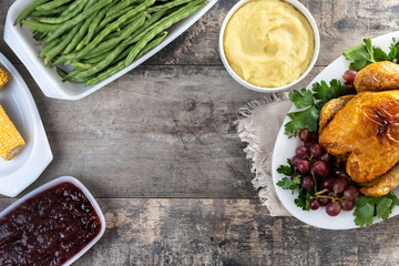 Thanksgiving roasted turkey with mashed potatoes, cranberry sauce and green beans on rustic wooden table. Top view. Copy space