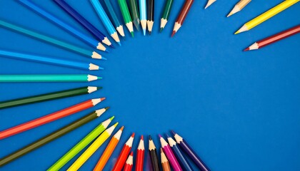 Assorted colored pencils arranged in a circular pattern on a vibrant blue backdrop