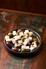 Green and kalamata olives and feta cheese on rustic wooden background. Soft focus.	