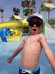Young caucasian male child enjoying water park with colorful slide