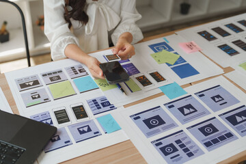 Web designer comparing mobile app design with a mobile phone