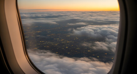 Aerial view from airplane window of clouds and city lights at dusk offering travel vibe