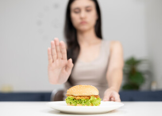 Woman is eating healthy. Close-up of woman pushing her burger with her hands and choosing healthy vegetables.