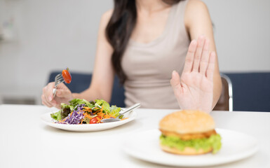 Woman is eating healthy. Close-up of woman pushing her burger with her hands and choosing healthy vegetables.