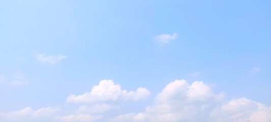 Beautiful natural sky view with bright blue and scattered tiny clouds. Panoramic sky background with scattered white clouds on a clear sunny day in summer.