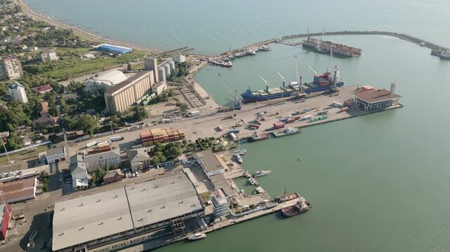 Poti, Georgia - 22nd august, 2025: Wide drone view of Poti seaport with breakwater, cranes, container stacks, grain silos, tanks, tugboats, marina, warehouses, rail links
