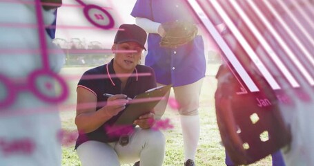 Female coach kneeling on field writing note and sparking data overlays showing charts to athletes - Powered by Adobe