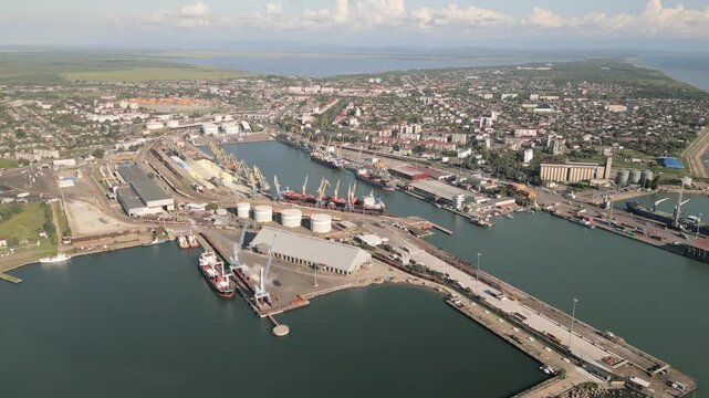 Poti, Georgia - 22nd august, 2025: aerial view Harbor basin with breakwaters, cranes, warehouse, fuel tank, rail tracks, coastline, ships offshore, Poti city seaport daylight logistics hub operations