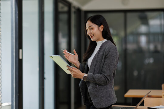 professional business asian woman looking at camera and smiling. businesswoman CEO holding digital tablet phone using fintech tab application standing at workplace in office.
 - Powered by Adobe
