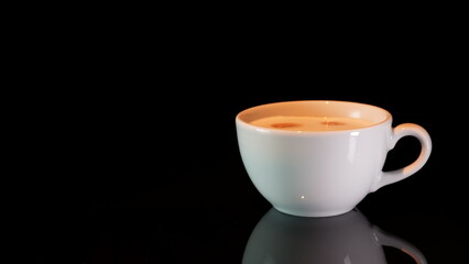 White coffee cup with cappuccino and coffee beans on black background with reflection