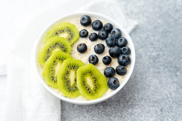 Oatmeal porridge with kiwi and blueberry served with white napkin