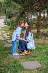 Fototapeta premium Mother and daughter wearing matching striped shirts and jeans while spending time together outdoors. Concept of family bonding, fashion harmony and casual everyday moments.