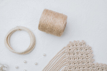 Macrame craft supplies with jute rope, pearls and wood rings on white background