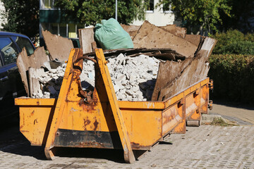 Container with construction debris. Yellow skip full of renovation waste. Outdoor disposal of rubble and trash. Industrial demolition and repair leftovers. Recycling of building material garbage. © Paweł Michałowski