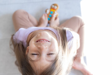 Fototapeta premium A girl is sitting on the floor with a gingerbread man in her hand. She is smiling, her head up, her eyes closed