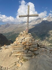 Summit view featuring the Croce di Arolley, a wooden cross mounted on a pile of rocks at high altitude in Valsavarenche, within the Gran Paradiso National Park, Aosta Valley, Italy