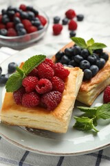 Yummy puff pastries with berries and mint on table, closeup