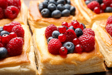 Tasty puff pastries with berries on table, closeup