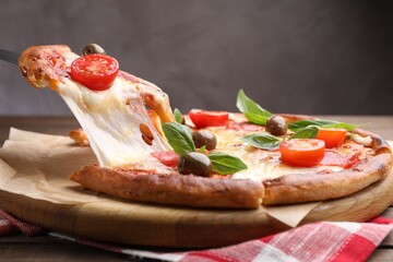 Taking piece of delicious pizza with cheese, salami, tomatoes and olives at table, closeup