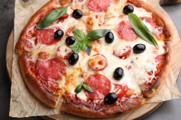 Delicious pizza with cheese, salami, olives and basil on grey table, closeup