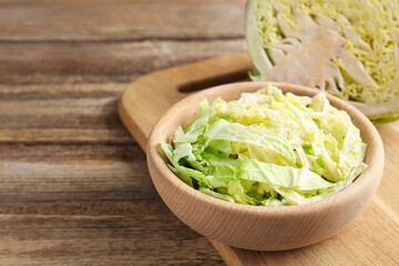 Cut Savoy cabbage on wooden table, closeup. Space for text