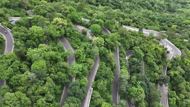 Drone shot of the serpentine ghat road at Kolli Hills, one of India's most challenging drives. The road is carved into the tropical, winding road is entirely surrounded by vibrant tropical forests