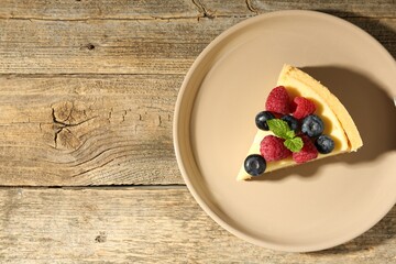 Piece of delicious cheesecake with fresh berries and mint on wooden table, top view. Space for text