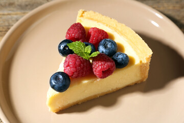 Piece of delicious cheesecake with fresh berries and mint on table, closeup
