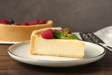 Piece of delicious cheesecake with fresh berries and mint on wooden table, closeup