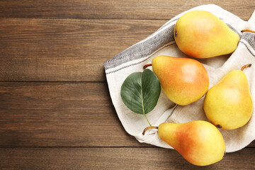 Many fresh pears and napkin on wooden table, top view. Space for text