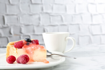Piece of tasty cheesecake with berries and sauce served on white marble table, closeup. Space for text