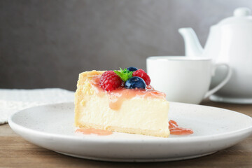 Piece of tasty cheesecake with berries and sauce on wooden table, closeup