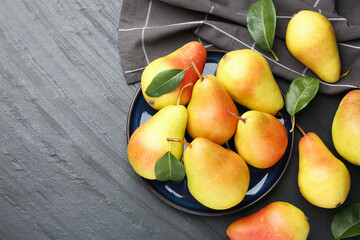 Many fresh pears and leaves on black table, flat lay. Space for text