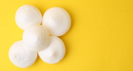 Yummy meringue cookies on yellow background, flat lay. Space for text