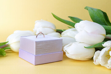 white tulips and engagement ring in a case on a light background