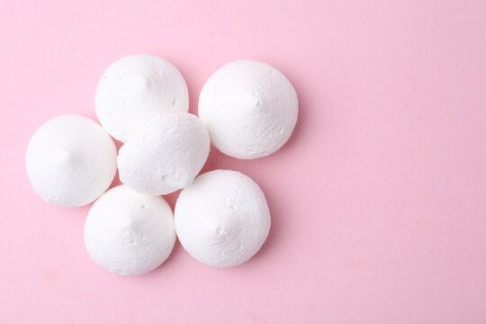 Many yummy meringue cookies on pink background, flat lay. Space for text